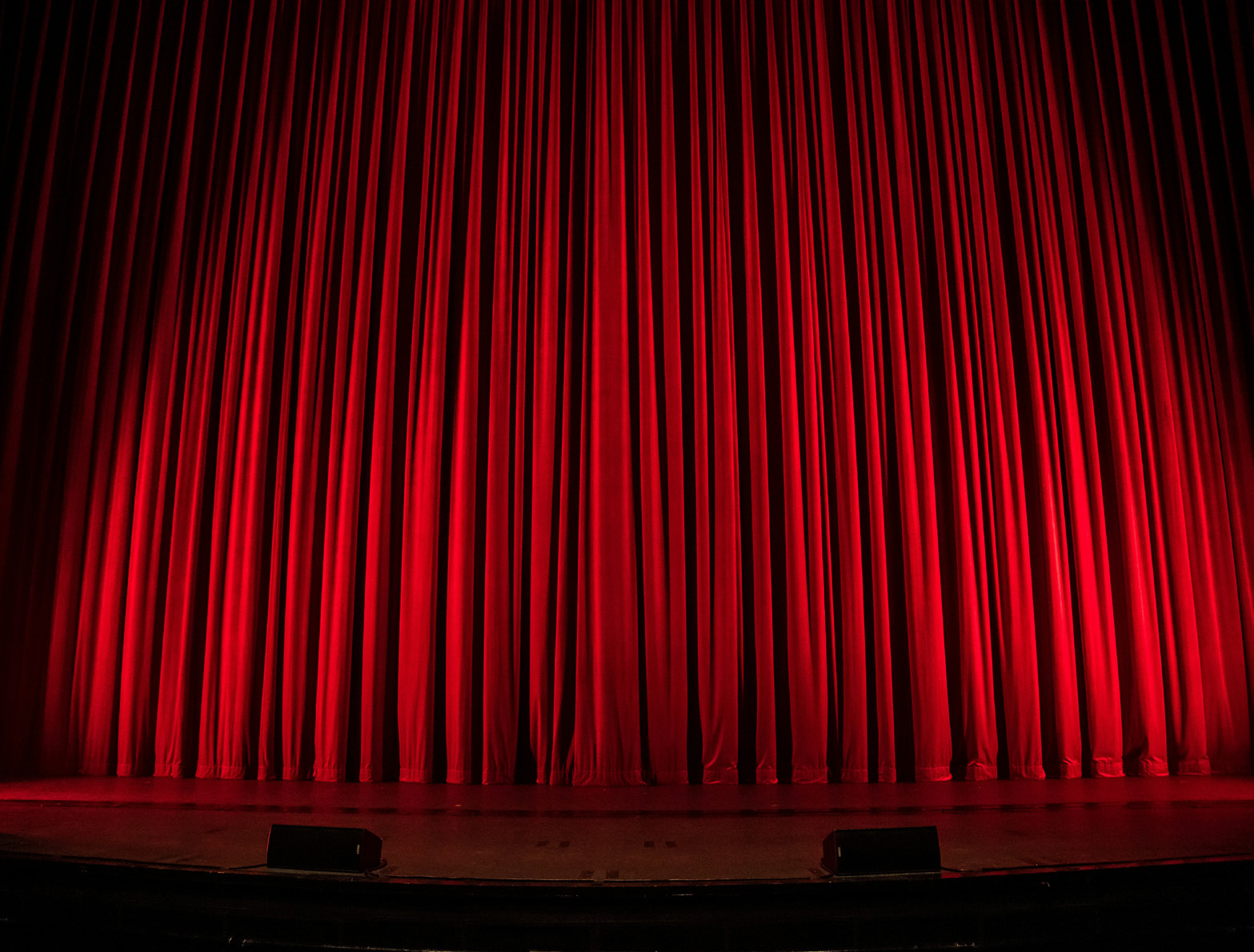 Rideau de théâtre rouge éclairé sur une scène